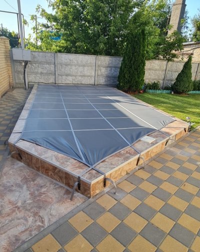 Прямоугольный бассейн с серым тентом, плиткой и зелеными растениями